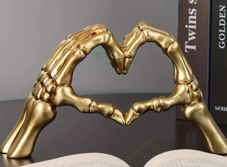Gold skeleton hands in a heart shape 