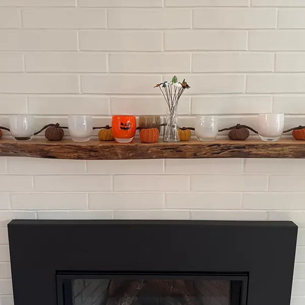 Fireplace with a wooden mantel decorated for Halloween against a white tiled wall.
